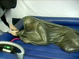 Woman struggling in a green latex bag